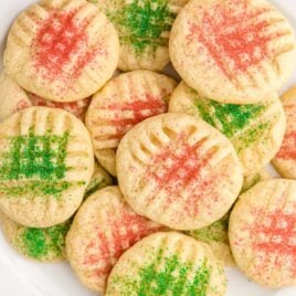 close up overhead shot of grandma's christmas sugar cookies piled on top of each other on a white plate