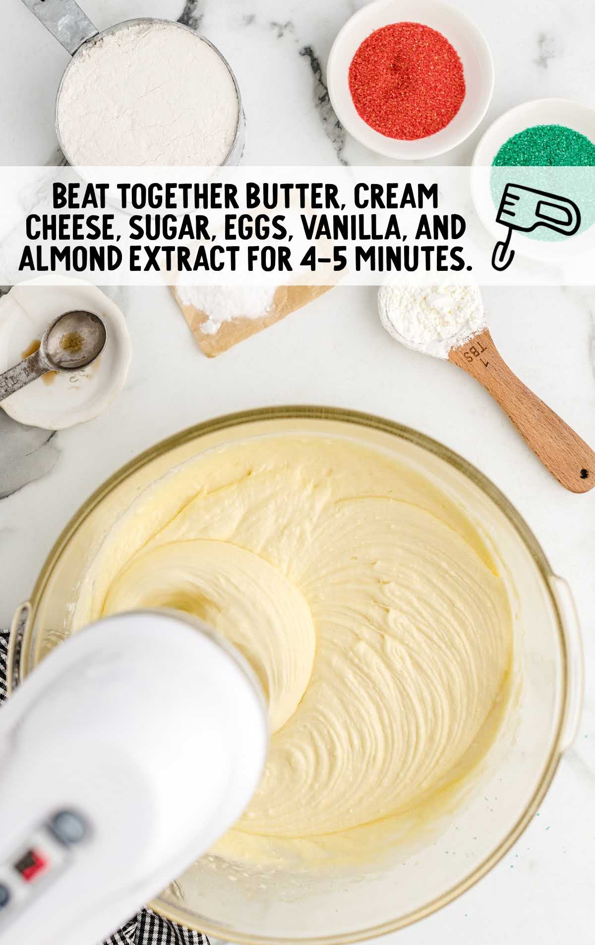 butter, cream cheese, sugar, eggs, vanilla, and almond extract blended together in a bowl