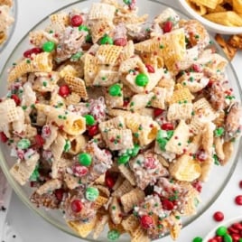 Large bowl of Christmas Chex Mix filled with crunchy cereal, pretzels, Bugles, M&Ms, and peppermint pieces.