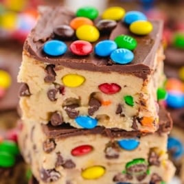 Close-up of two stacked cookie dough bars loaded with chocolate chips and mini M&M's.