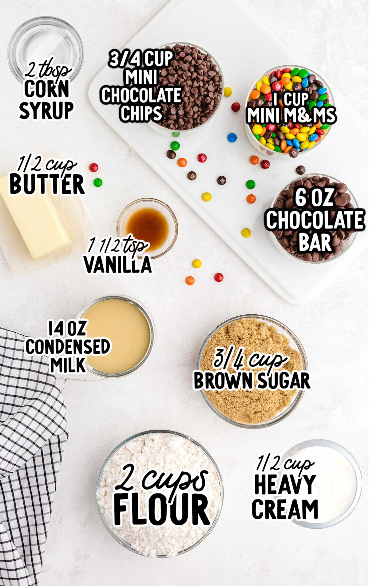 Flat lay of measured ingredients for cookie dough bars including flour, butter, brown sugar, condensed milk, and mini M&M's.