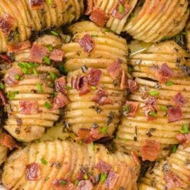 close up overhead shot of Hasselback Potato Casserole garnished with bacon bits and green onions in a baking dish