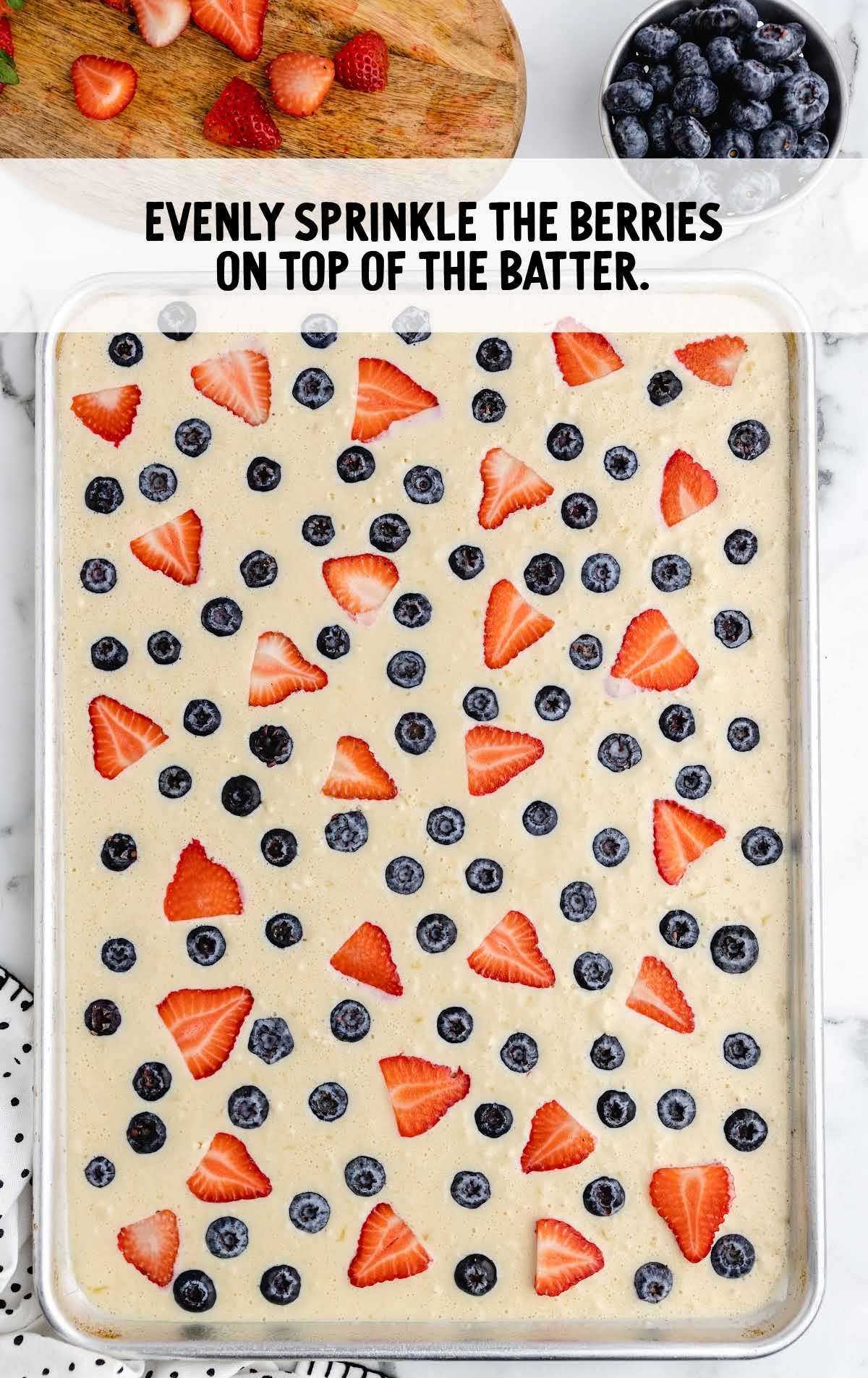 berries sprinkled on top of the pancake batter in the baking sheet