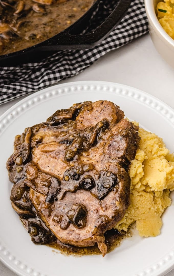 smothered pork chops on a white plate