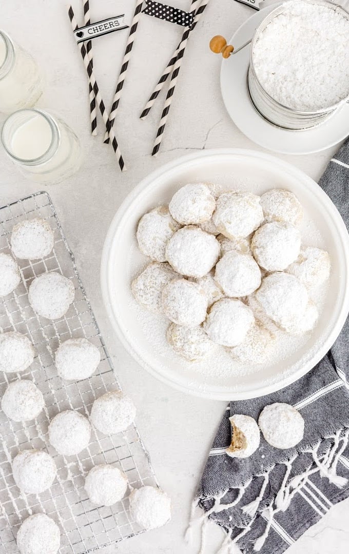overhead shot of snowball cookies piled on top of each other and on a wire rack