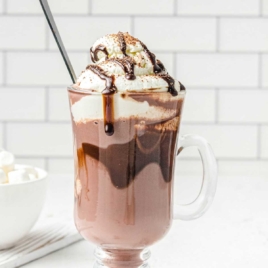 a close up shot of Spiked Hot Chocolate in a tall mug topped with chocolate syrup