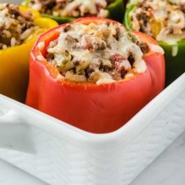 close up shot of Stuffed Peppers topped with melted cheese in a baking dish