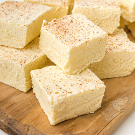 close up shot of eggnog fudge piled on top of each other on a wooden board