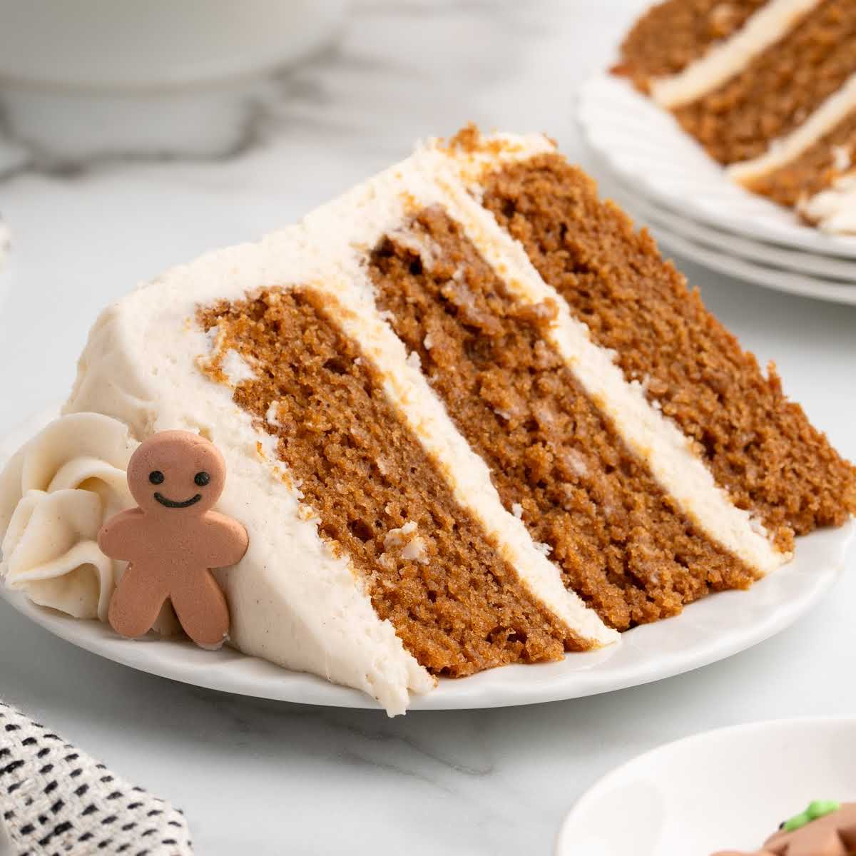 Slice of gingerbread cake with cream cheese frosting and a small gingerbread man decoration.