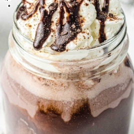 a close up shot of Spiked Hot Chocolate in a tall mug topped with chocolate syrup