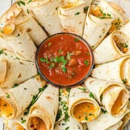 over head shot of blooming quesadilla ring arranged on a plate with dipping sauce in the middle