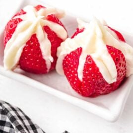 close up shot of two Cheesecake Stuffed Strawberries on a serving tray