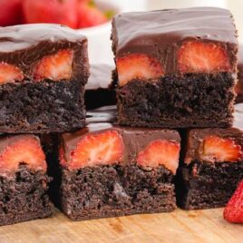 close up shot of Chocolate Covered Strawberry Brownies stacked on top of each other on a wooden board