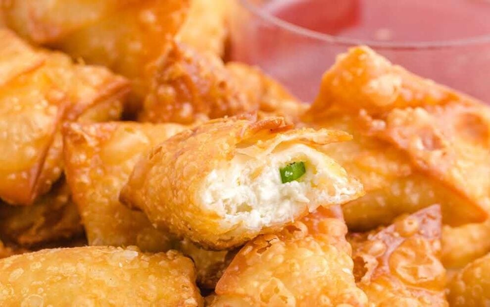 close up shot of a plate of Crab Rangoon served with a small bowl of sweet Thai chili sauce