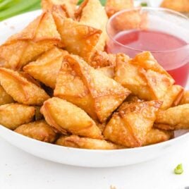 close up shot of a plate of Crab Rangoon served with a small bowl of sweet Thai chili sauce