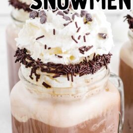 close up shot of dirty snowmen in glass mason jars drizzled with chocolate topped with whip cream and sprinkles