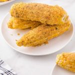 close up shot of Fried Corn on the Cob on a white plate