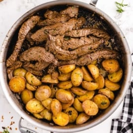 close up overhead shot of garlic butter steak and potatoes in a skillet