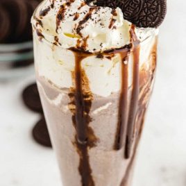 close up shot of Oreo milkshake topped with a Oreo and chocolate glaze falling down the cup