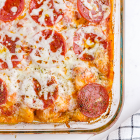 close up shot of pizza casserole with biscuits in a clear baking dish