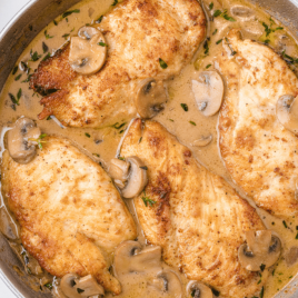 close up overhead shot shot of chicken marsala with sauce and mushrooms on top in a dish