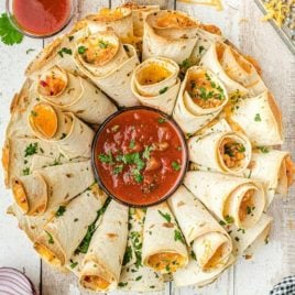 over head shot of blooming quesadilla ring arranged on a plate with dipping sauce in the middle