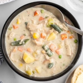 Finished chicken pot pie soup in a bowl with spoon showing thick, creamy texture