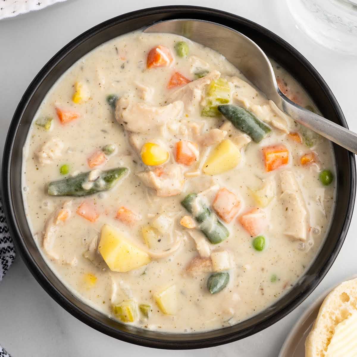 Finished chicken pot pie soup in a bowl with spoon showing thick, creamy texture