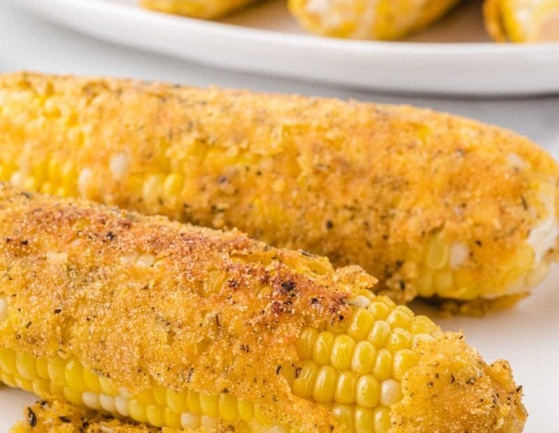 close up shot of fried corn on the cob on a white plate