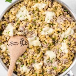 close up overhead shot of philly Cheesesteak Pasta in a pot with a large wooden spoon