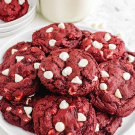 close up shot of red velvet cookies with white chocolate chips stacked on top of each other on a plate