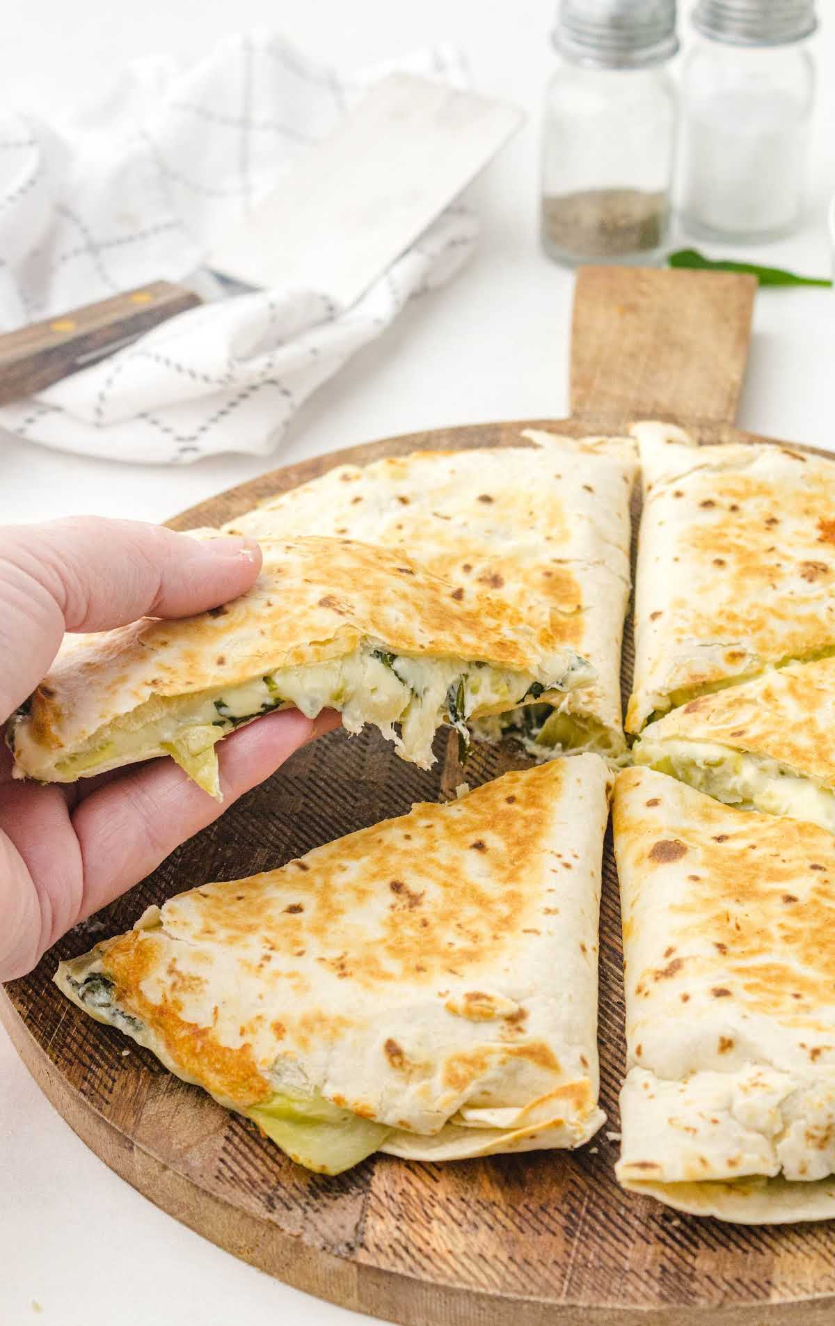 close up shot of spinach artichoke quesadillas on a wooden board