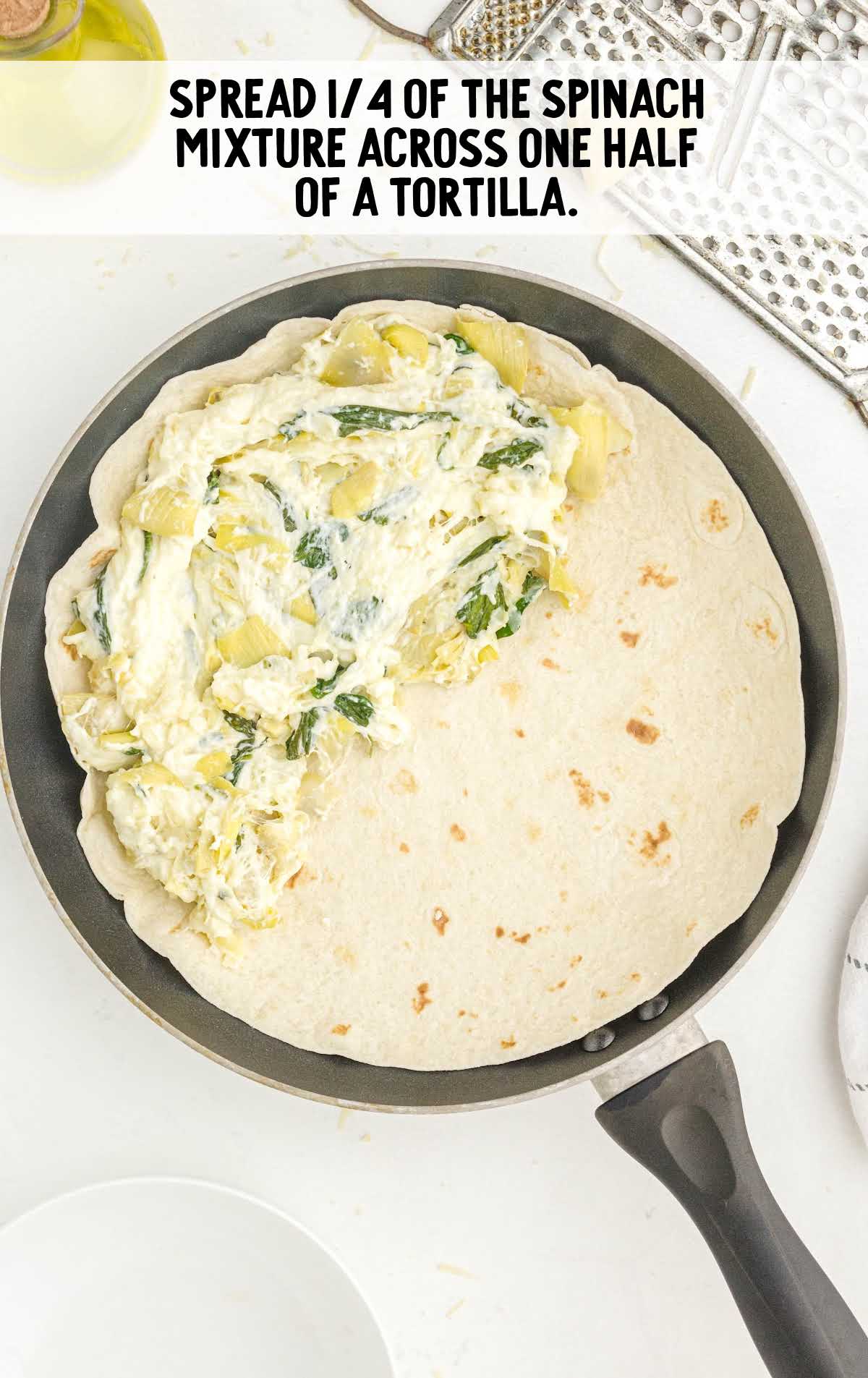 spinach artichoke mixture placed on top of a tortilla in a pot
