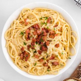 overhead shot of a bowl of Carbonara Pasta topped with bacon bits, cheese, and parsley