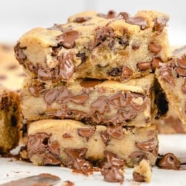 Overhead view of sliced chocolate chip cookie bars with chocolate chips on a parchment-lined surface.