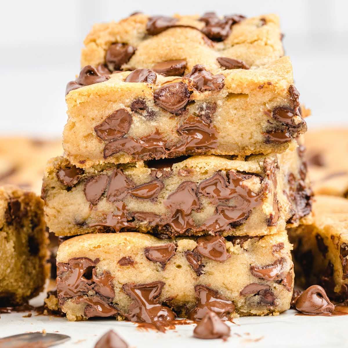 Ingredients for chocolate chip cookie bars displayed on a marble surface, including butter, sugar, flour, and chocolate chips.