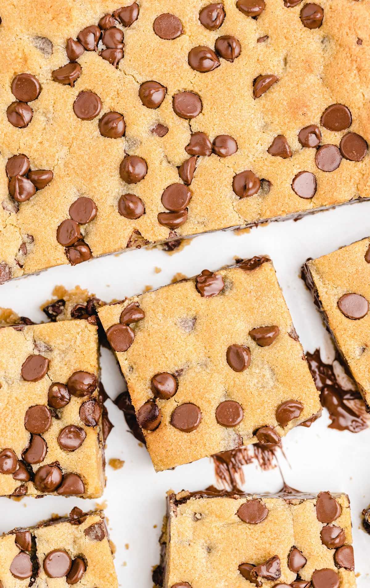 Close-up of thick chocolate chip cookie bars stacked on top of each other, loaded with melted chocolate.