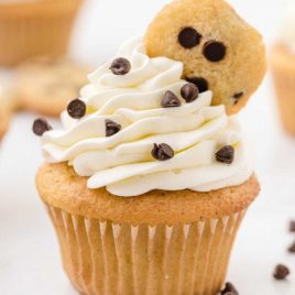 close up shot of cookie dough cupcakes topped with whipped cream frosting and a mini chocolate chip cookie