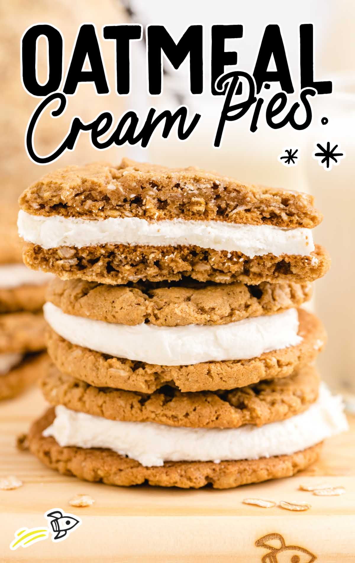 close up side shot of oatmeal cream pies stacked on top of each other on a board with a piece taken out of the top pie