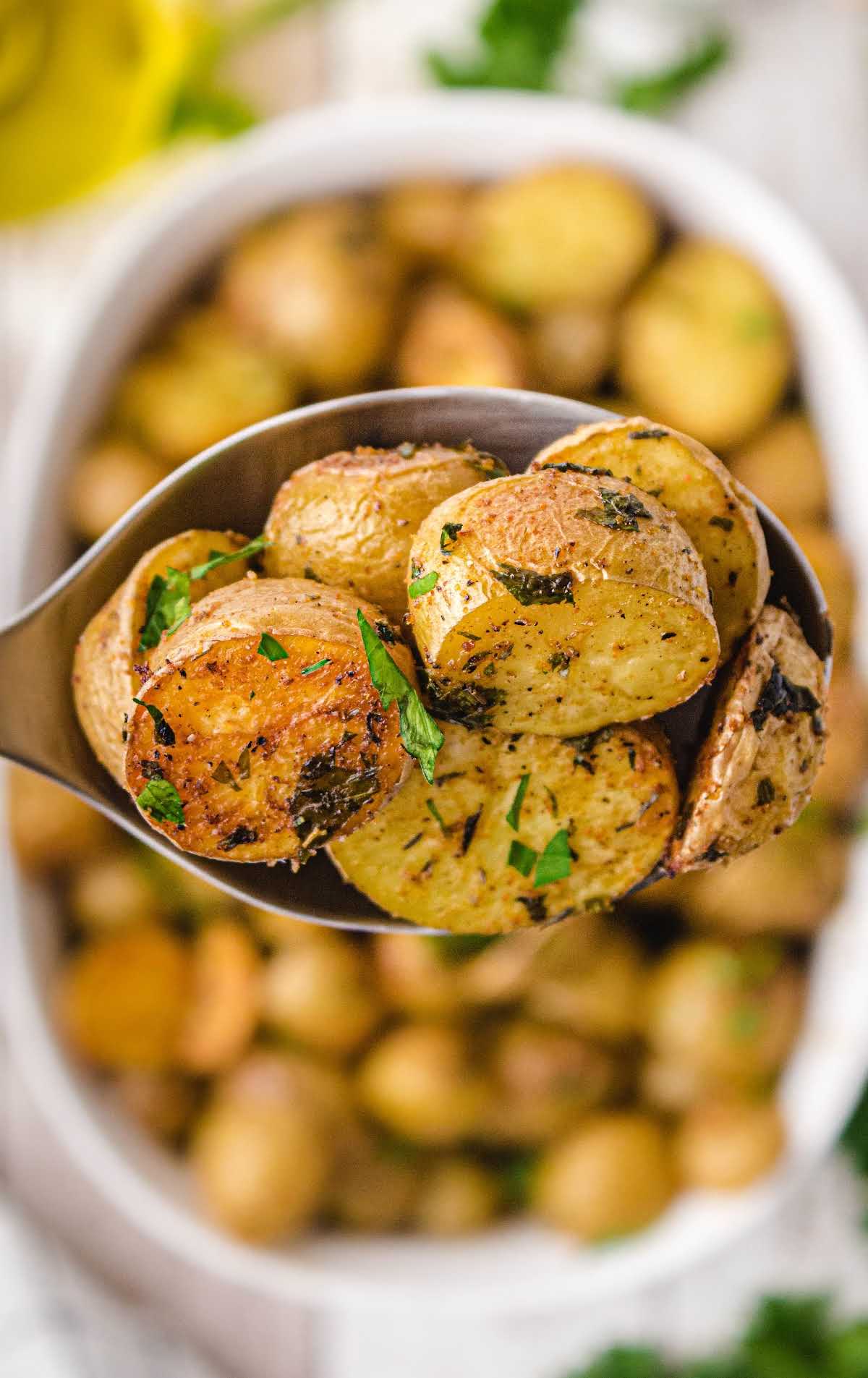 close up shot of roasted potatoes garnished with parsley on a spoon