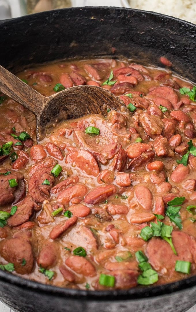 close up shot of red beans and rice garnished with green onions in a pan