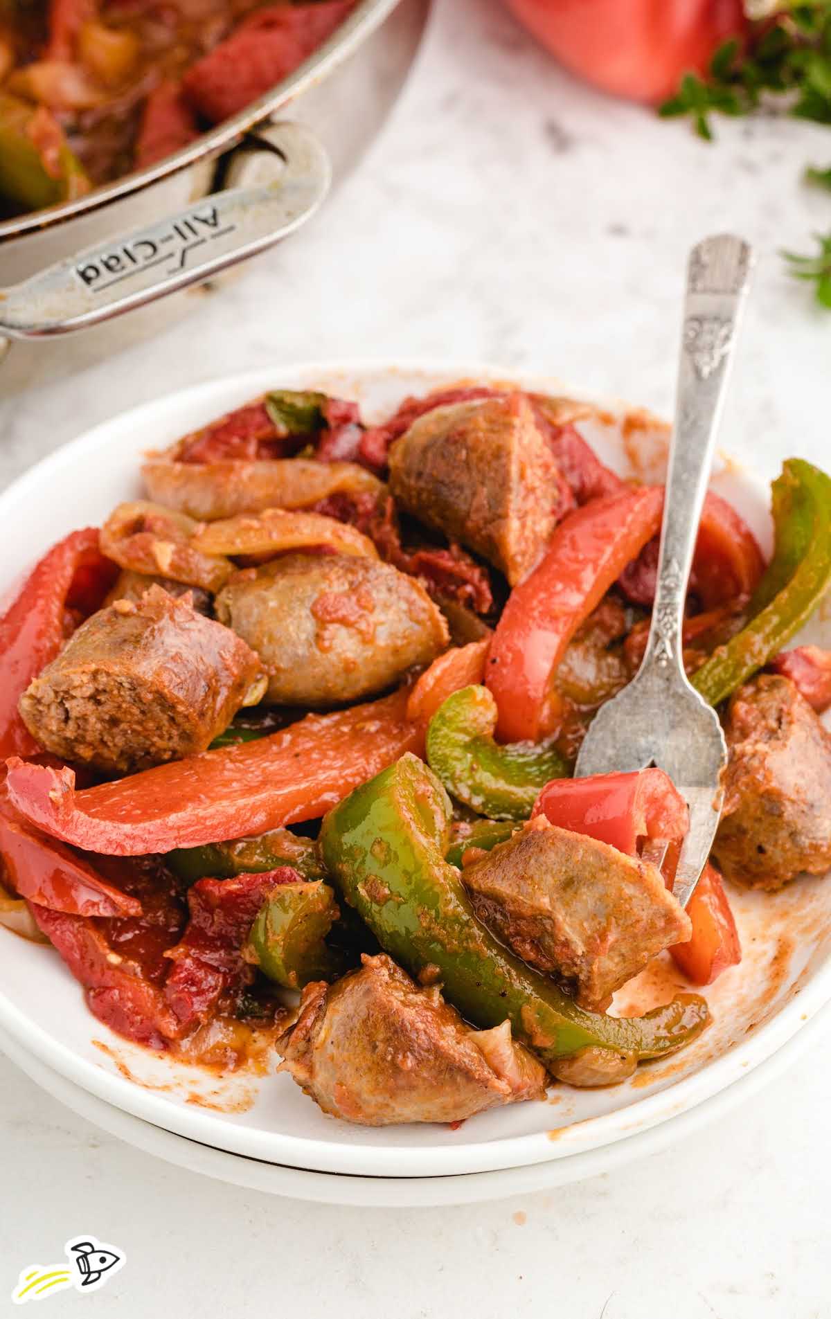 a plate of sausage and peppers with a fork