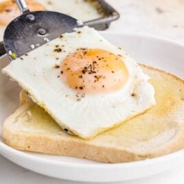 close up shot of a Sheet Pan Eggs being placed on a slice of bread on a plate
