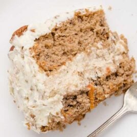 overhead shot of carrot cake cheesecake slice on a white plate with a fork