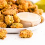 fried pickles stacked on top of each other with dipping sauce on a plate