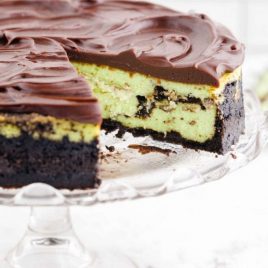 close up shot of mint chocolate cheesecake with a slice taken out of it on a cake dish