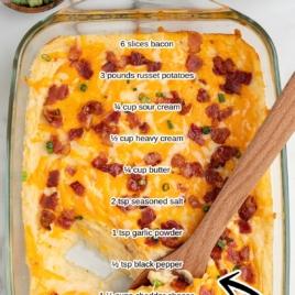 A glass baking dish filled with cheesy Twice Baked Potato Casserole, topped with chopped bacon and green onions. Ingredients are labeled on the casserole, and a wooden spoon is in the dish. Text reads “The Best Twice Baked Potato Casserole Recipe.”.