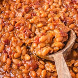 close up shot of a baking dish of Baked Beans with a wooden spoon