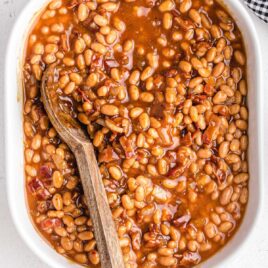close up overhead shot of a baking dish of Baked Beans with a wooden spoon