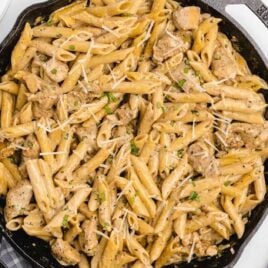 a skillet of chicken pasta garnished with basil